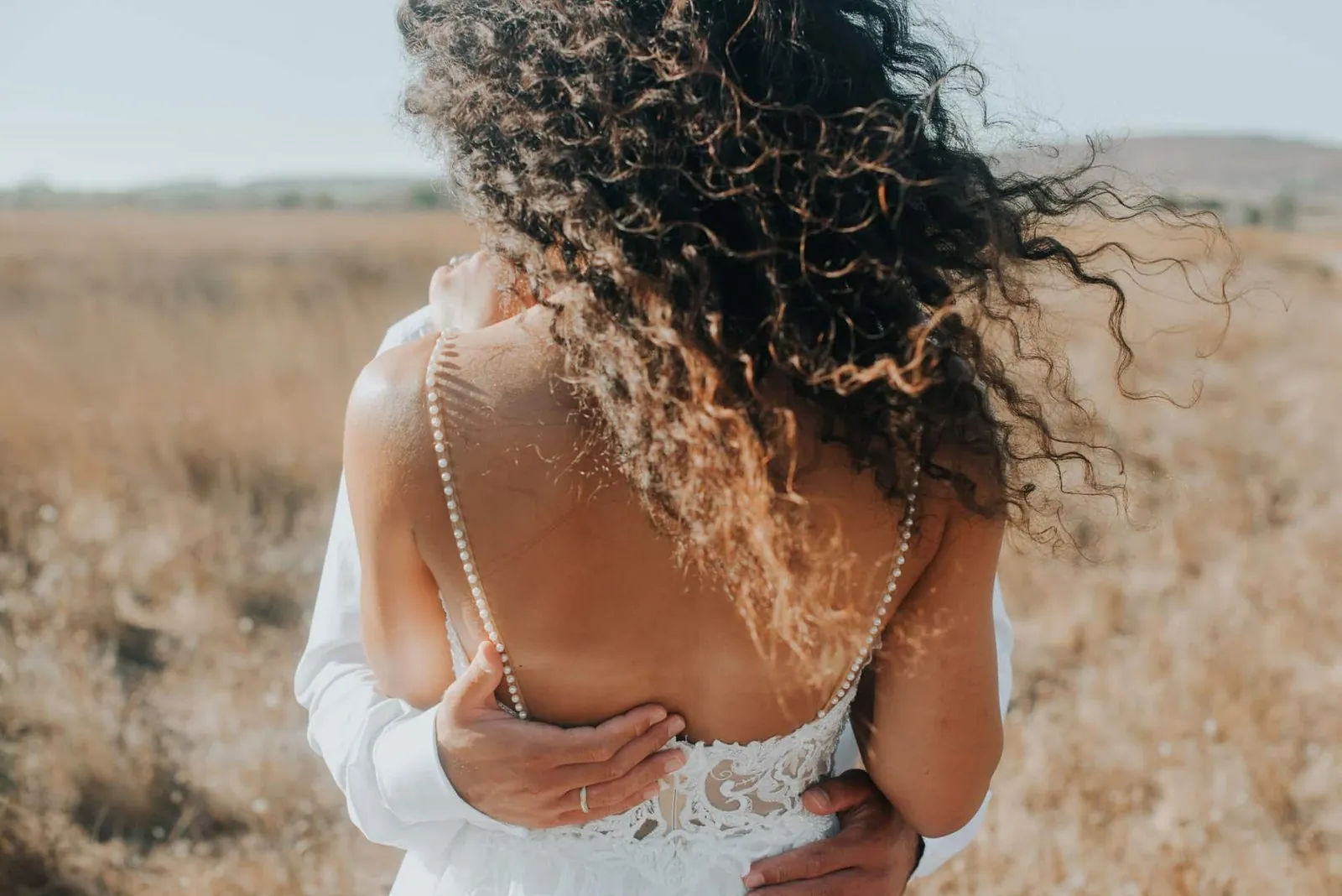 Groom embracing bride from behind on Greek beach