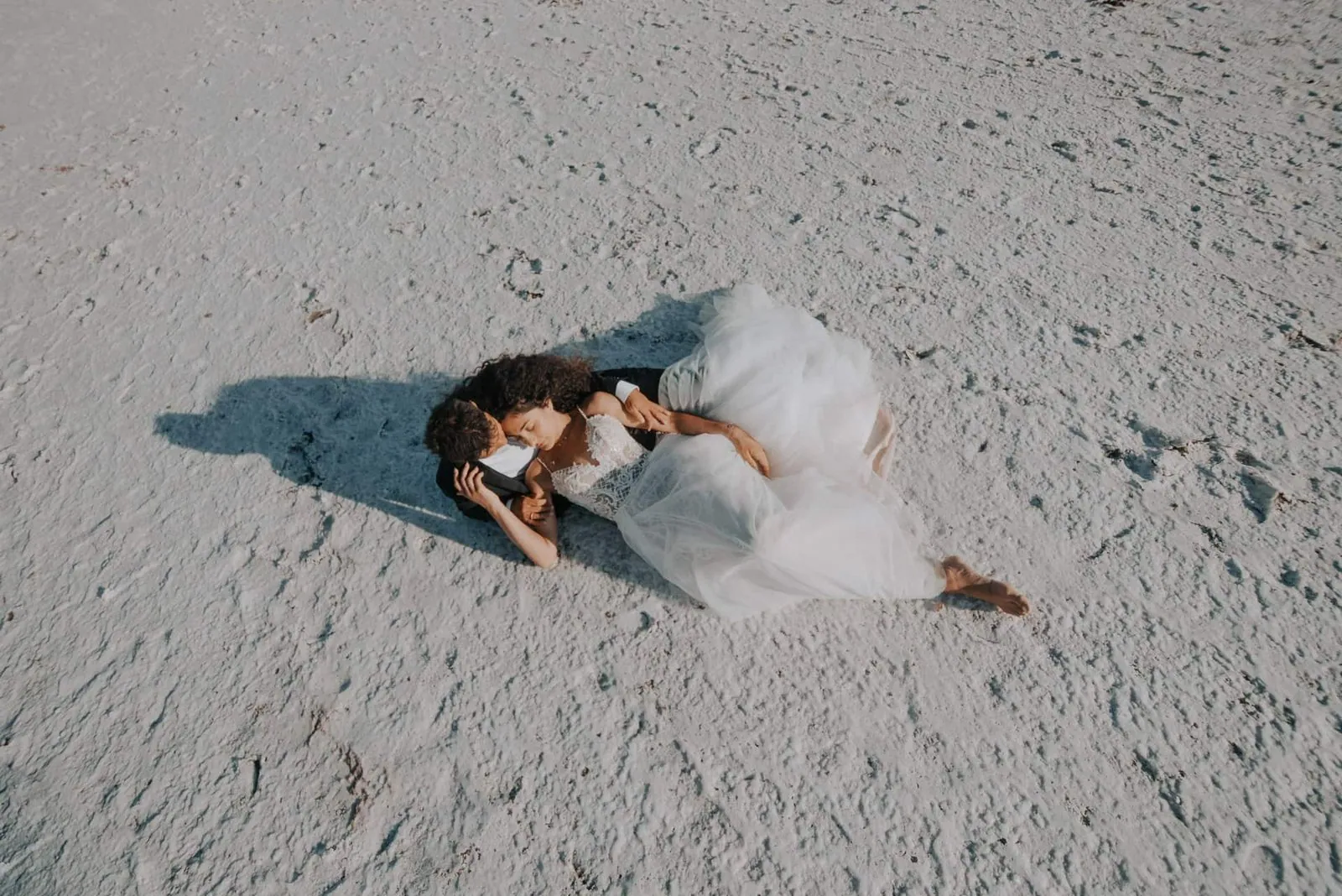 Bird's eye view of couple embracing and kissing on white salt flats