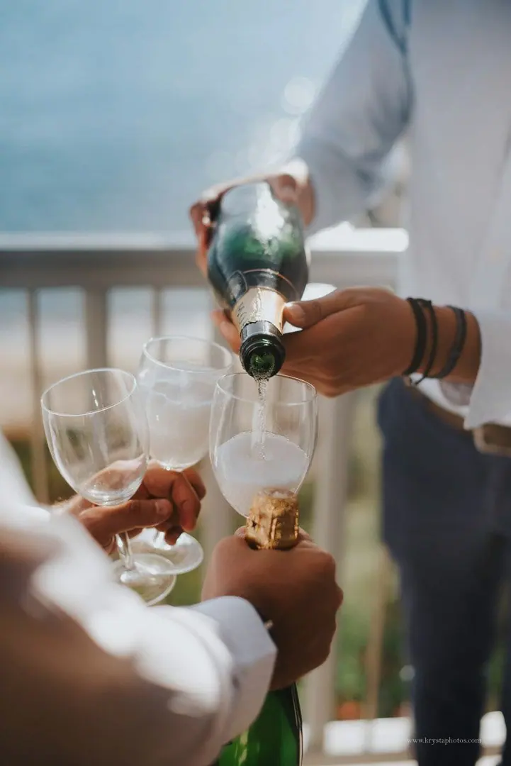 Groomsmen opening champagne during wedding prep with sea view